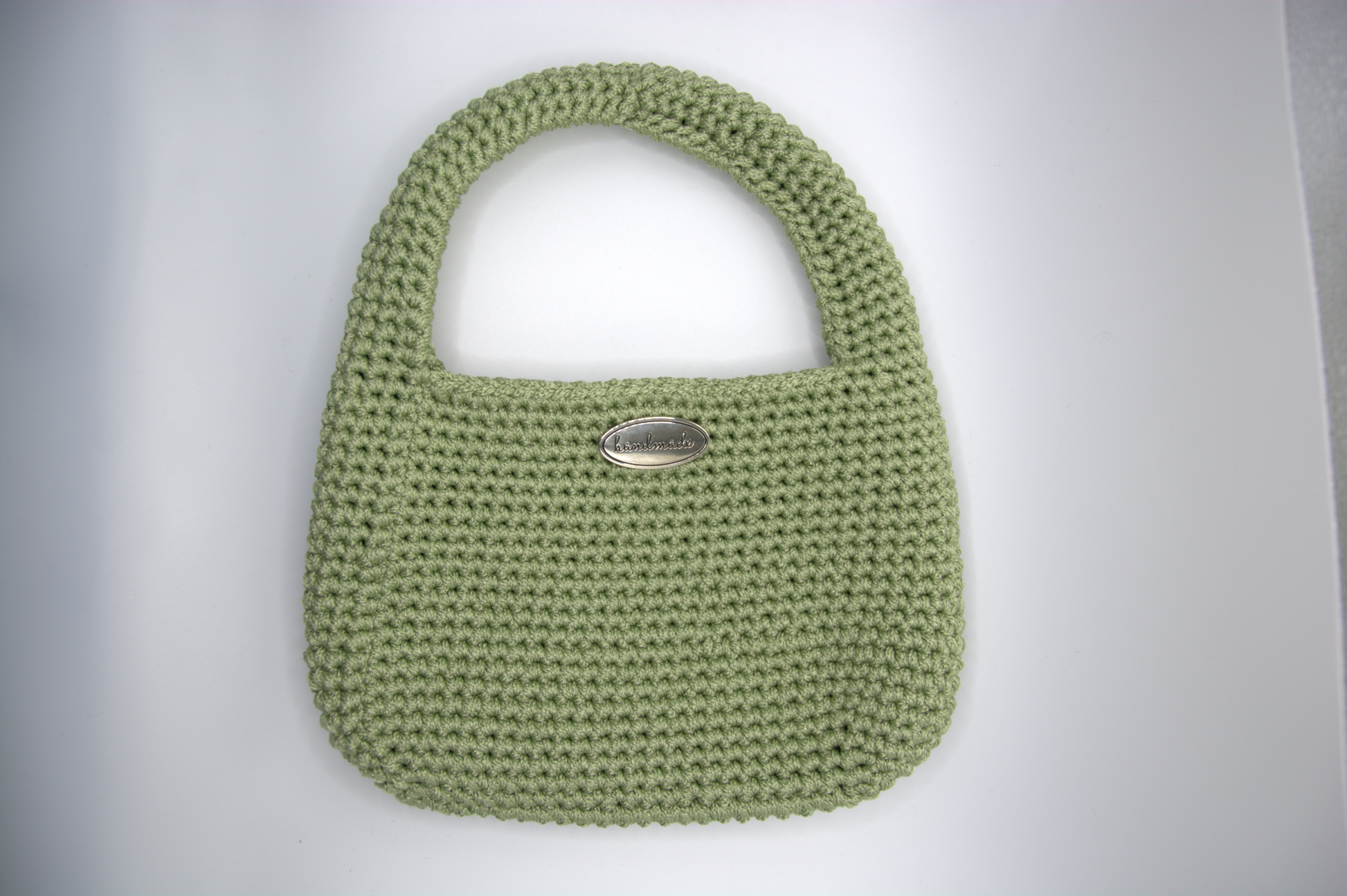 Mini bag color salvia all'uncinetto con manico integrato vista frontale