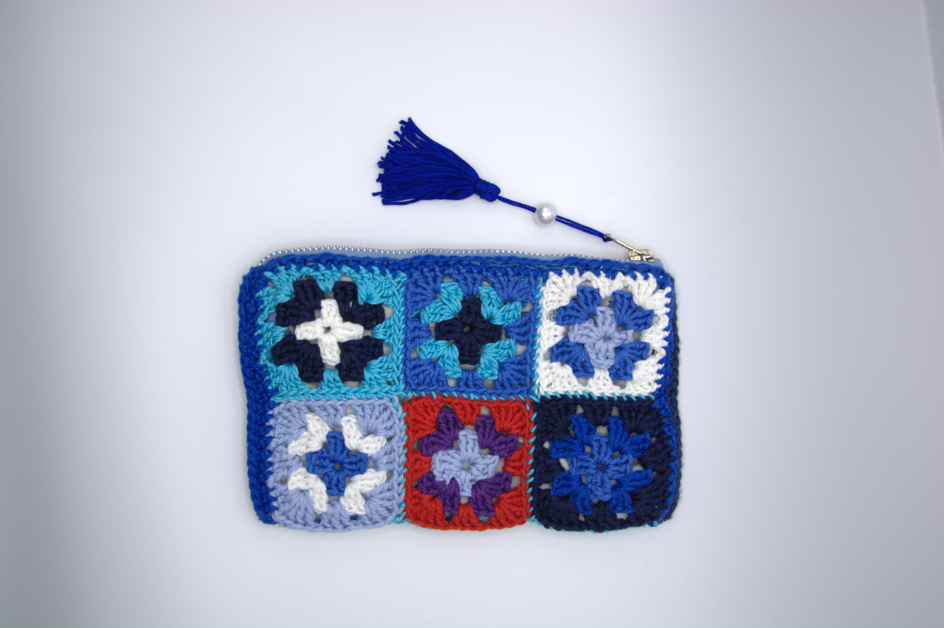 Pochette blu notte all'uncinetto con fiori granny a contrasto e nappina