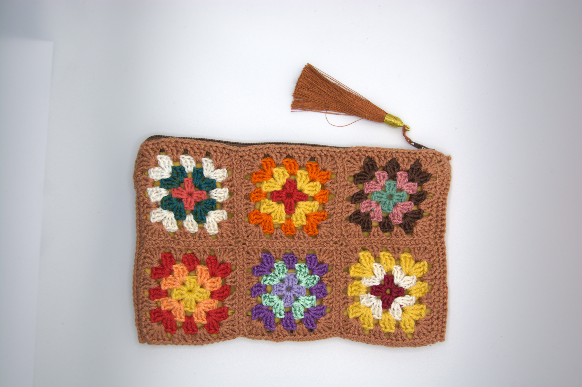 Dettaglio della pochette color terra con fiori granny zip e nappina